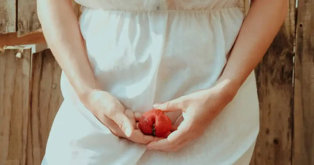 femme qui tient une fraise dans les mains pour imager une vulve